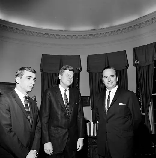 President John F. Kennedy standing in the Oval Office with two visiting Australian newspapermen.