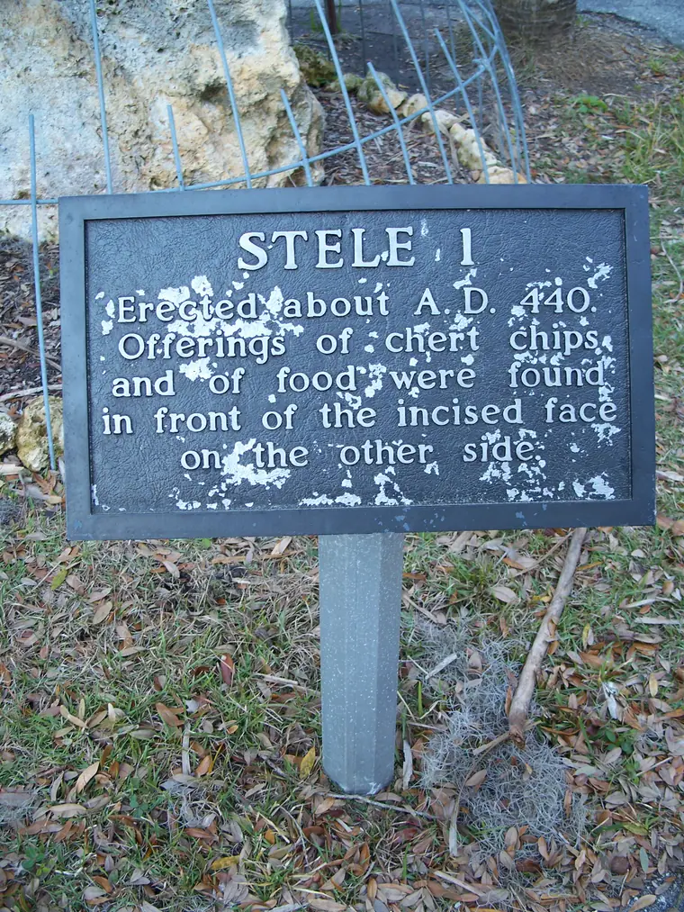 A tall upright carved stone marker standing among trees at Crystal River Archaeological State Park in Florida.
