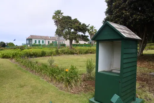 A second view of Longwood House on Saint Helena, showing the shuttered facade and surrounding grounds.