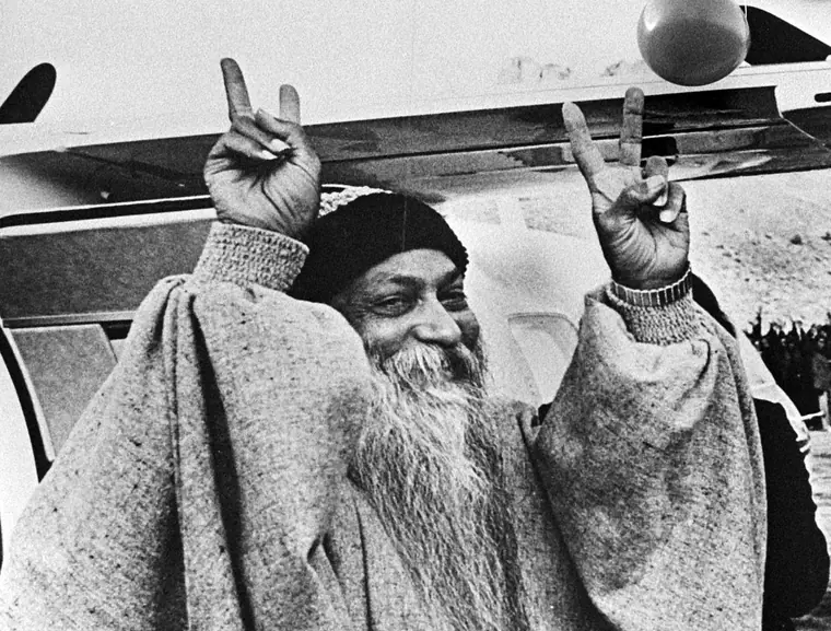 Portrait photograph of Osho Rajneesh, bearded, in a dark robe, from a Dutch national archives press image.