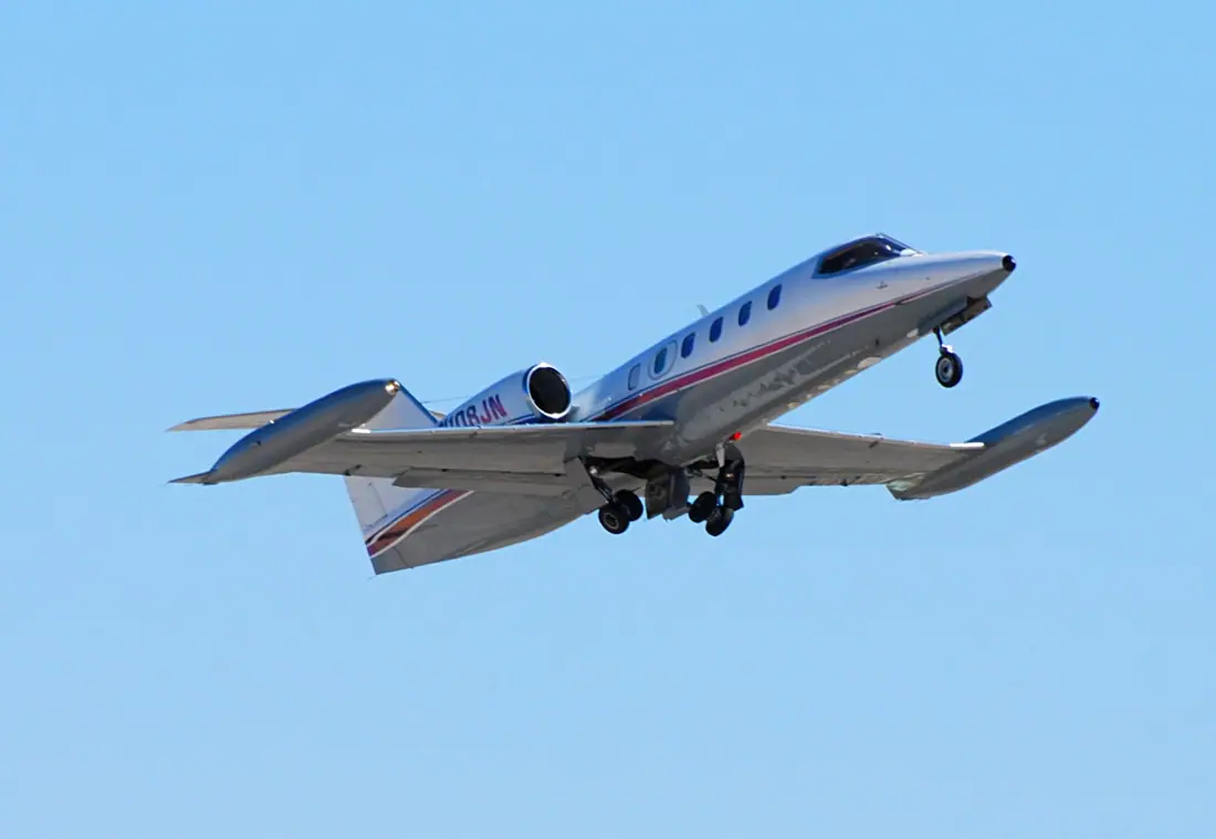 A small white twin-engine business jet with tip tanks parked on an apron.