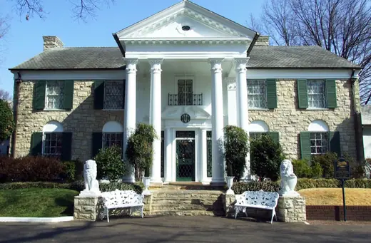 Graceland seen from the front lawn on a clear day, with visitors on the drive.