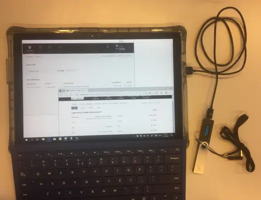 A laptop screen showing a bitcoin transaction being sent from an exchange account to a hardware wallet device sitting beside it.