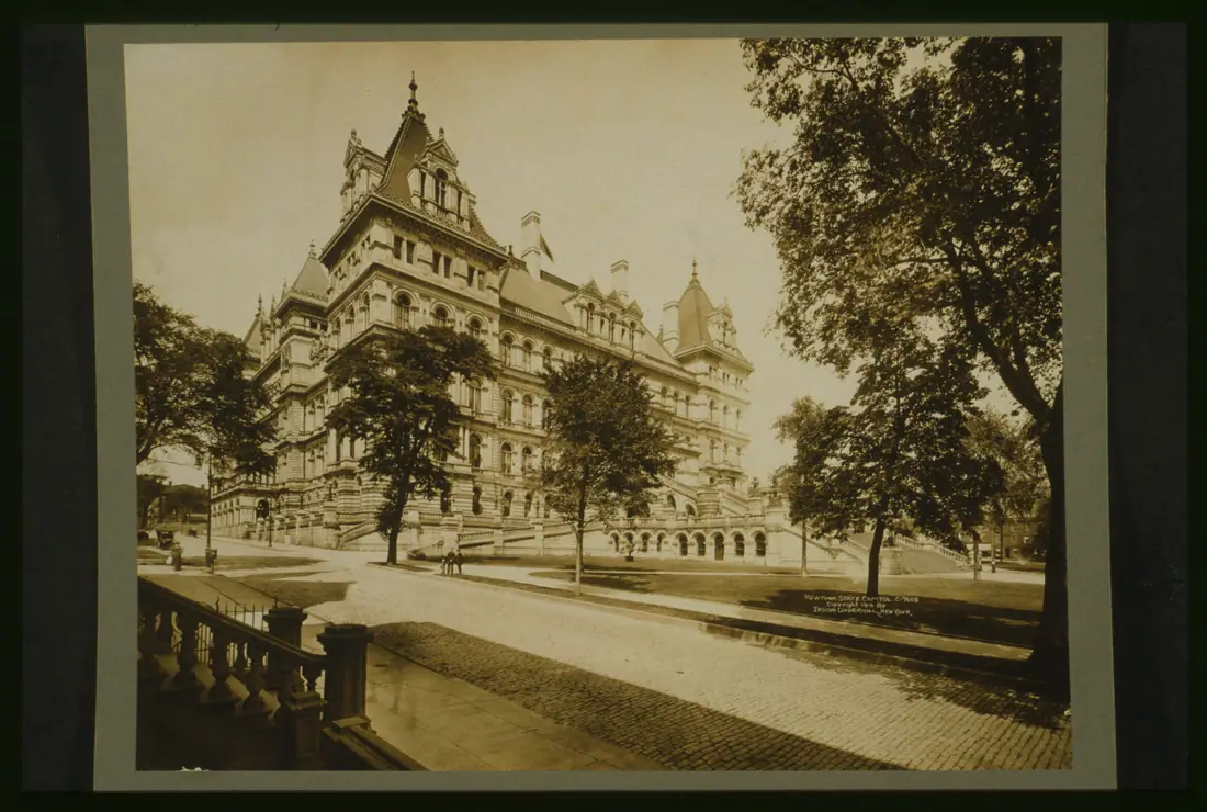 A large nineteenth-century stone capitol building photographed in black and white from across a public square.