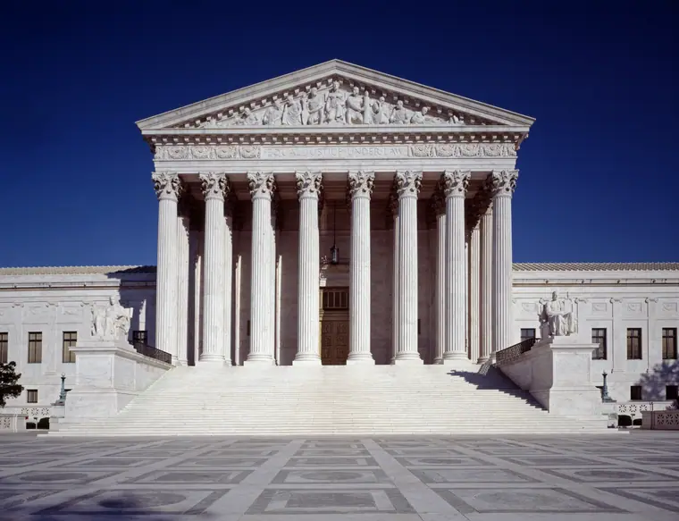 The marble west front of the United States Supreme Court building, with its columned portico and pediment.