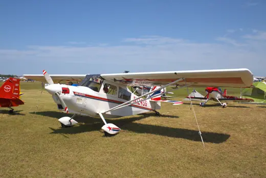 A single-engine American Champion 8KCAB Super Decathlon light aircraft parked on a ramp.
