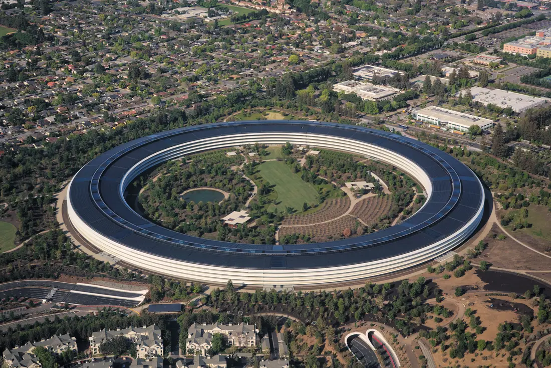 Aerial photograph of the circular Apple Park headquarters building in Cupertino, its roof covered in solar panels.