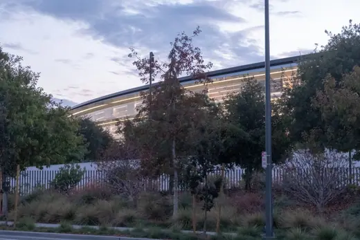 Ground-level view of the curved glass facade of Apple Park.