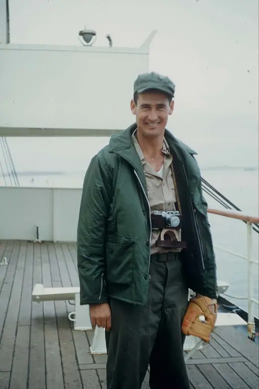 Man in a flight suit and Marine Corps cap standing beside military aircraft.