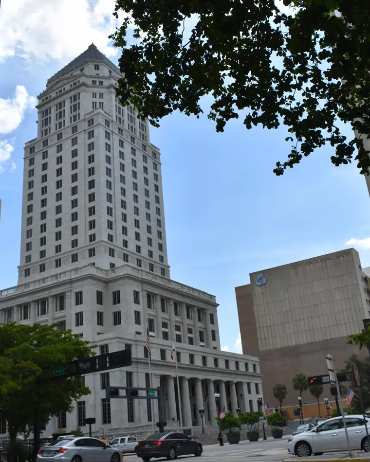 A tall stepped neoclassical courthouse tower of pale stone rising above downtown streets.