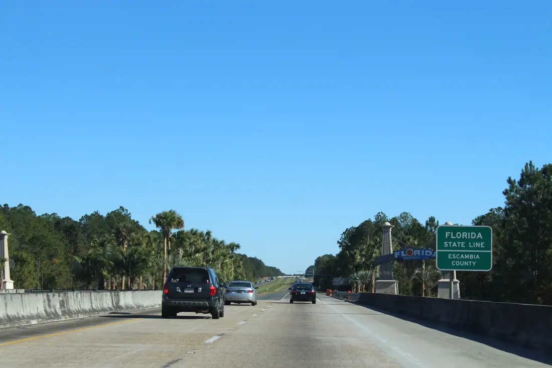 The Alabama–Florida state line on eastbound Interstate 10 near Pensacola, marked by a roadside sign.