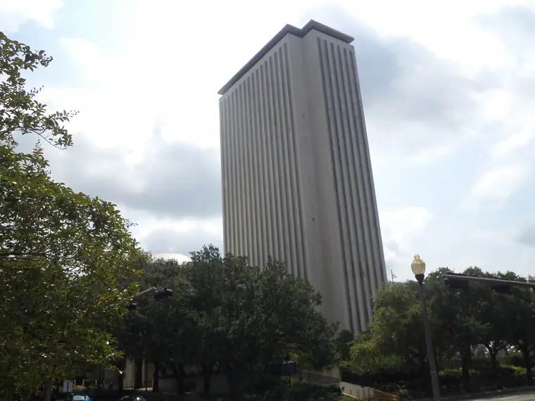 The tall modern Florida State Capitol tower rising behind the low historic Capitol, seen from Kleman Plaza.