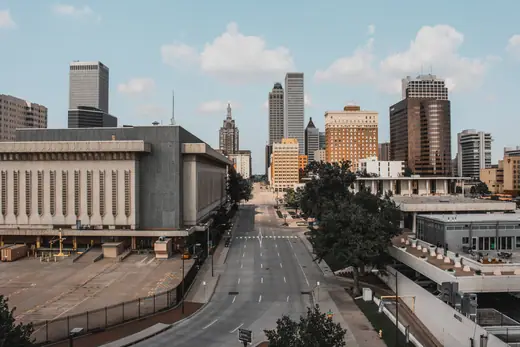 The downtown Tulsa skyline seen across open ground, with mid-rise office towers under a blue sky.