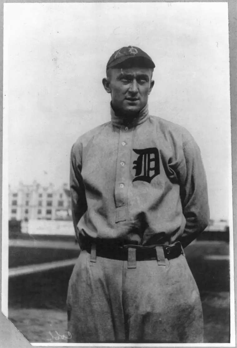Portrait of Ty Cobb in a Detroit baseball uniform, arms folded, looking at the camera.