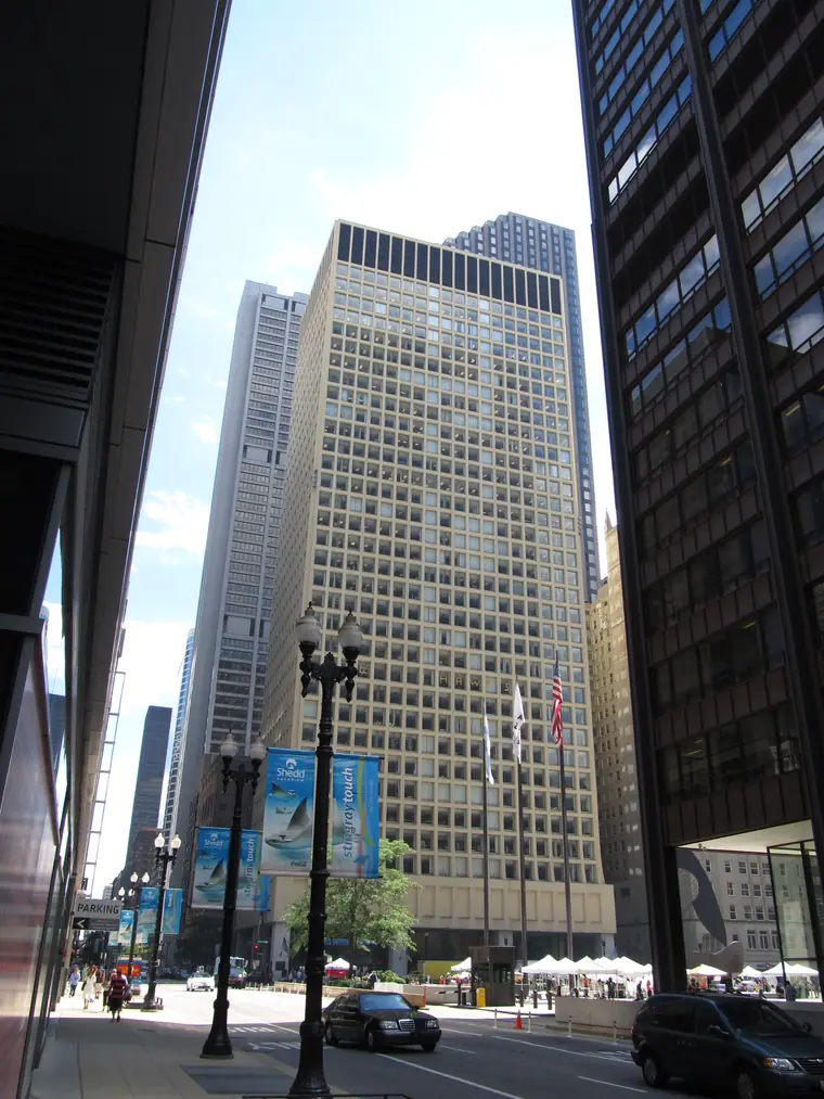 A thirty-one storey tower clad in weathered rust-brown steel rising above a city plaza.