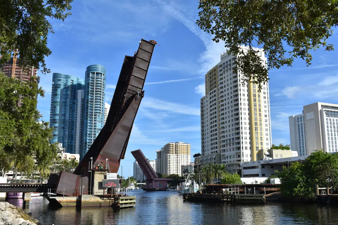 Drawbridges raised over the New River in Fort Lauderdale, Florida, with boats waiting to pass.